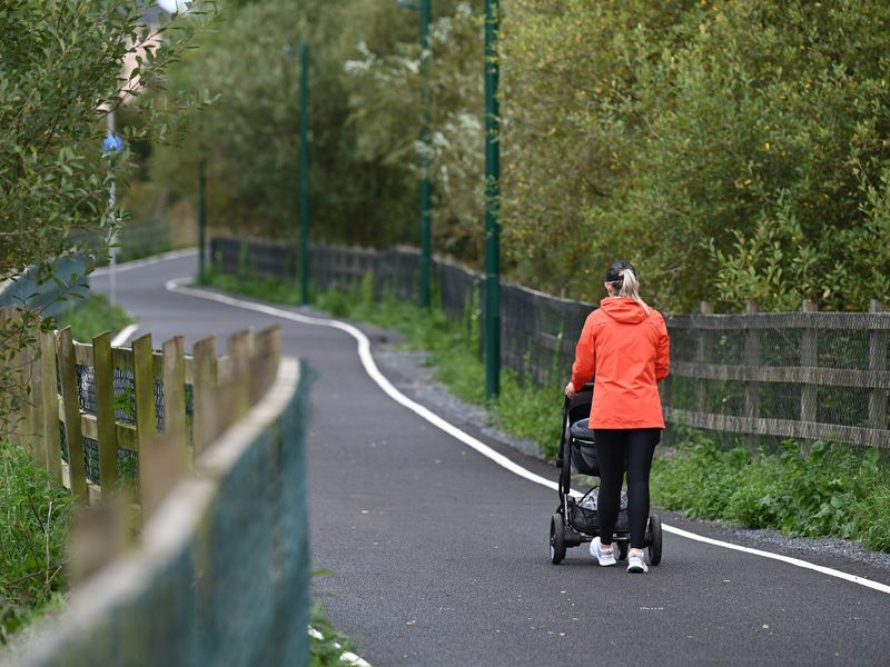 Citizen walking along the Ulster Canal Greenway pushing a pram
