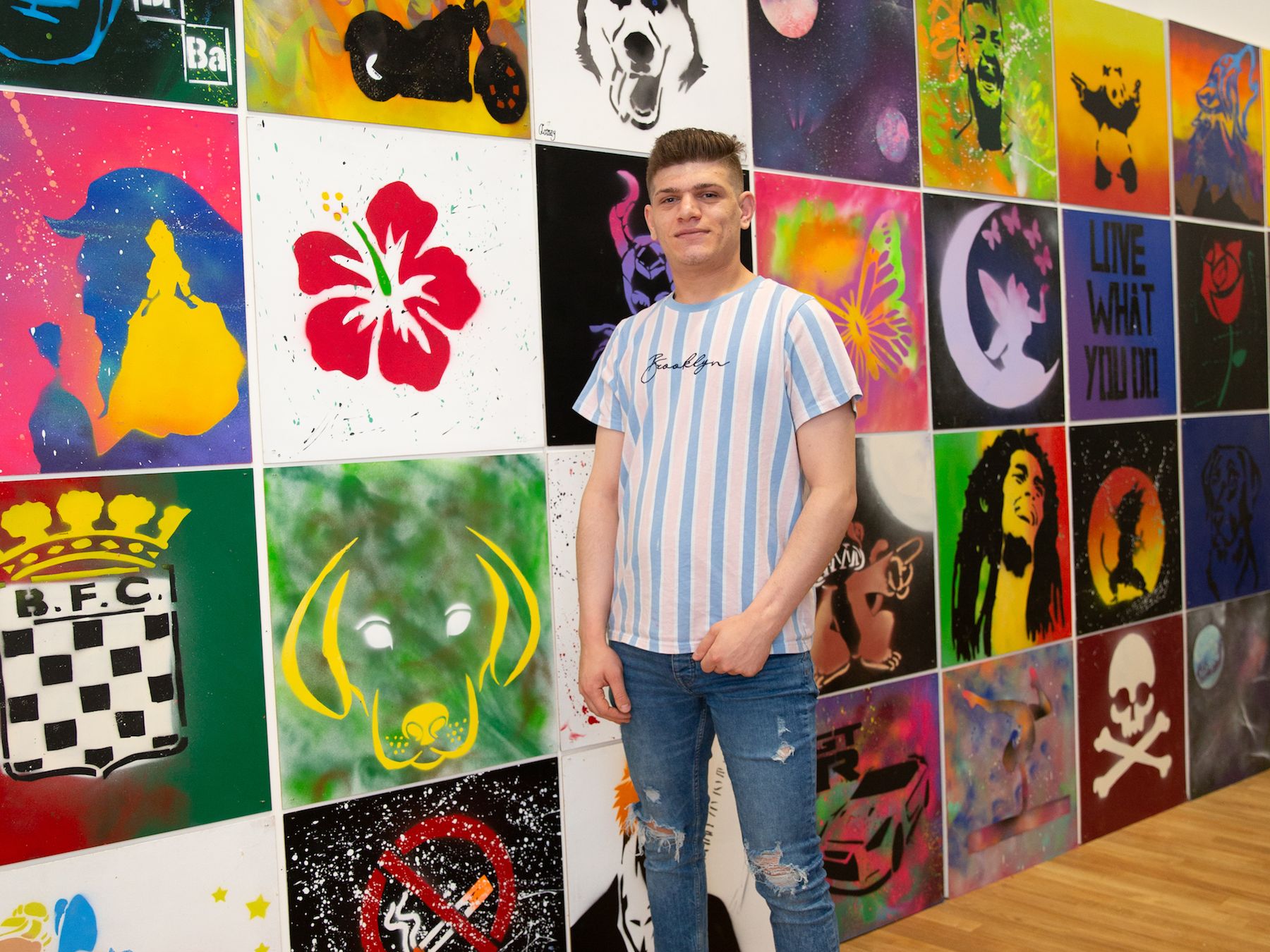 young person from Youthscape project with colourful artwork displayed in the background