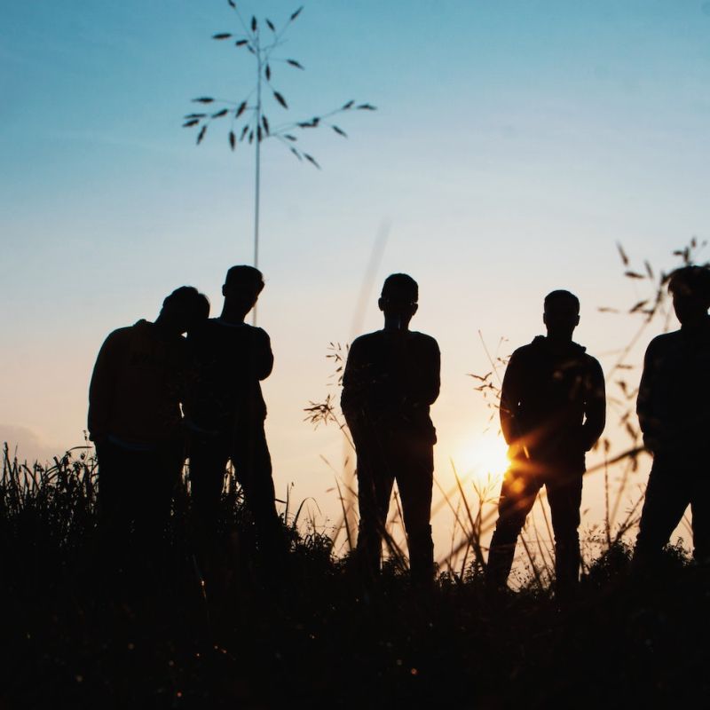 Group of young people standing together in the sunset